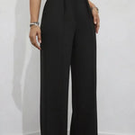 Person wearing black wide-leg pants against a white wall