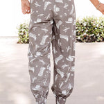 Person wearing gray pants with white patterns on a light background