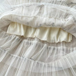 Close-up of a layered white skirt with ruffles on a dark background