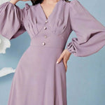 Woman wearing a lavender dress with long sleeves against a light blue background