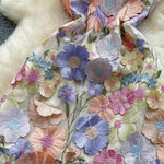 Close-up of a fabric with colorful floral embroidery on a textured background.