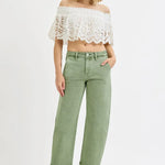 Woman wearing a white lace top and green pants on a white background
