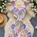 Floral dress on a hanger with flowers and a hat in the background