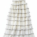 White ruffled dress with black trim on a textured surface