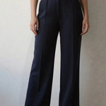 Person wearing navy wide-leg pants and a white shirt against a neutral background