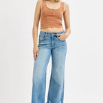 Woman wearing a brown tank top and blue jeans on a white background