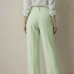 Person wearing a white shirt and light green pants against a plain background