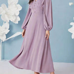 Woman wearing a long, light purple dress with balloon sleeves against a light blue background.