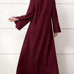 Maroon long-sleeve dress worn by a person against a light wooden panel background