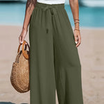 Person wearing olive green wide-leg pants on a beach.