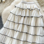 White tiered skirt with black trim on a fluffy white surface