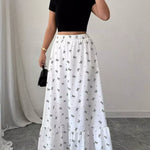 Woman wearing a black crop top and white skirt with butterfly pattern indoors.
