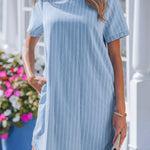 Woman wearing a blue striped dress standing outdoors with flowers in the background