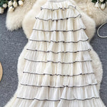 White ruffled dress with black trim on a textured surface