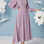 Woman wearing a long, light purple dress with a blue background and white flowers.