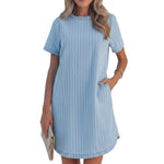 Woman wearing a light blue striped dress with a blurred outdoor background