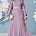 Woman wearing a long lilac dress with balloon sleeves against a light blue background with white floral decorations.